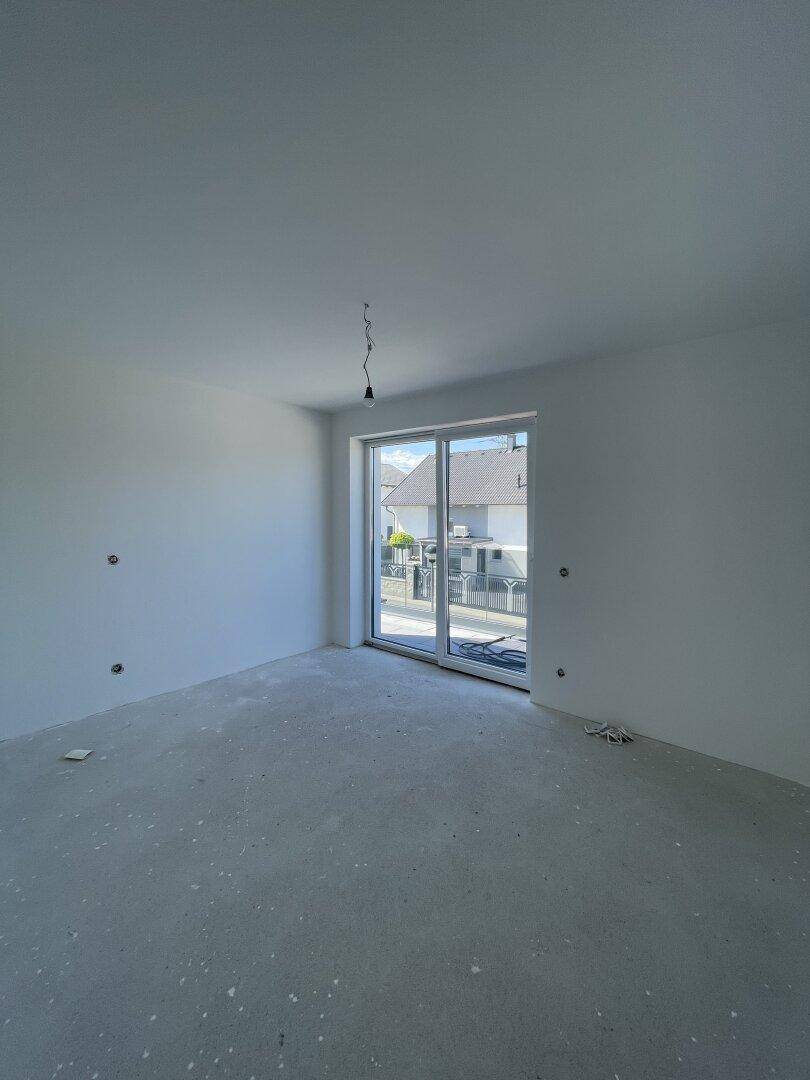 Unfertiger Wohnraum mit großen Fenstern und viel Tageslicht.