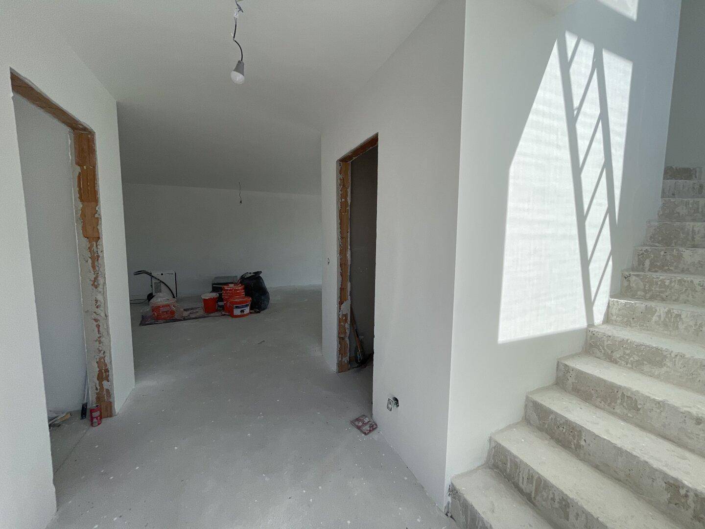 Unfertiger Flur mit Betontreppe und viel Tageslicht.