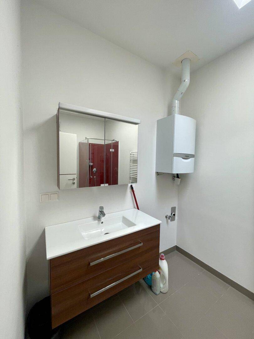 Funktionaler Raum mit Waschbecken, Spiegelschrank und Gastherme, ideal als Hauswirtschaftsraum.
