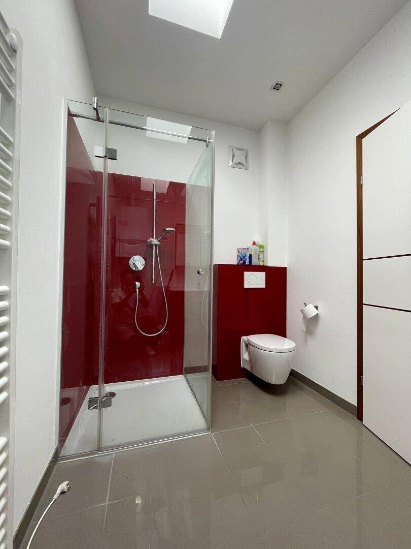 Modernes Badezimmer mit begehbarer Dusche, wandhängendem WC und beheiztem Handtuchhalter.
