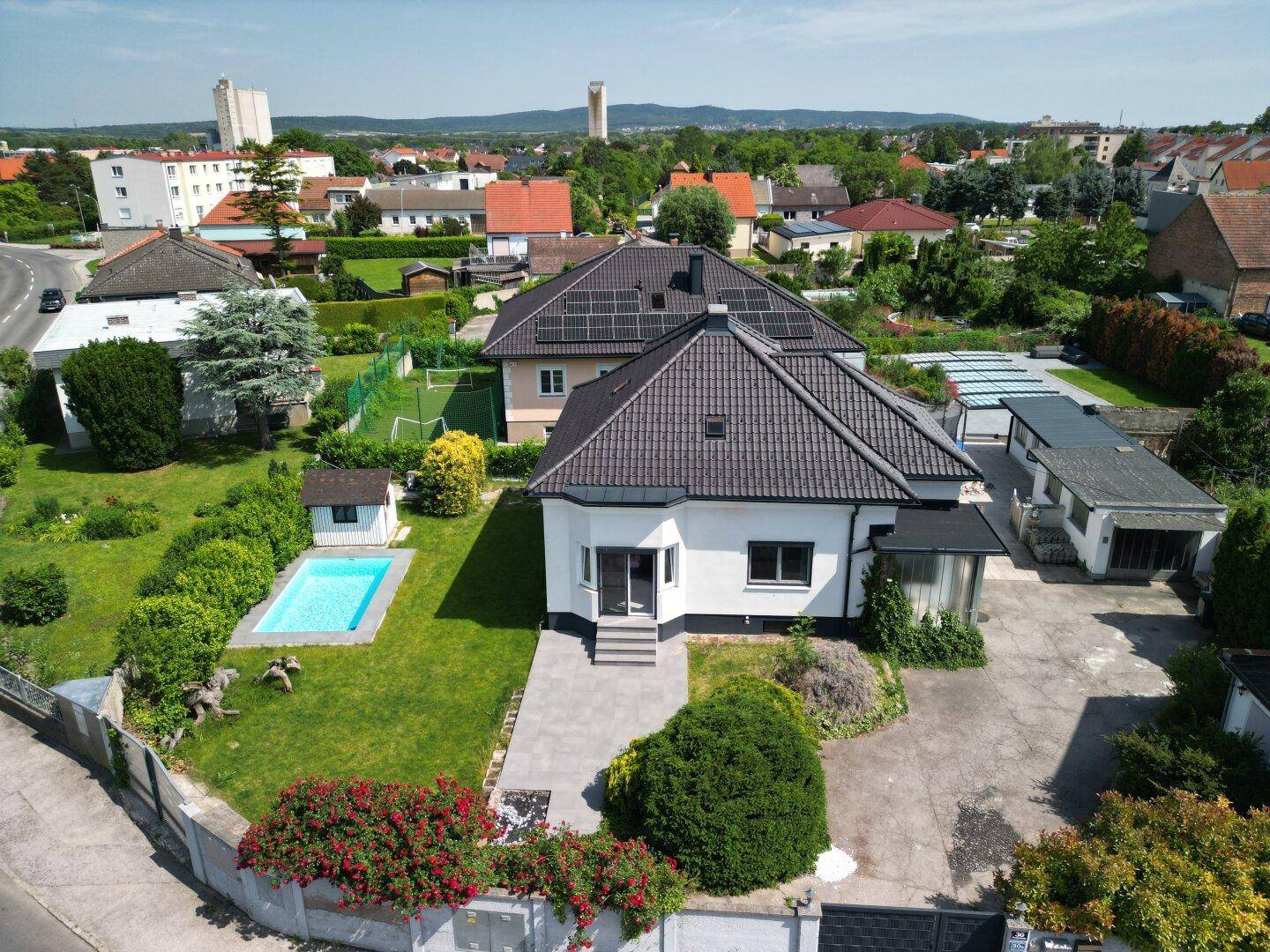 Luftaufnahme des Hauses mit Garten, Pool und Photovoltaikanlage auf dem Nachbardach in ländlicher Umgebung.