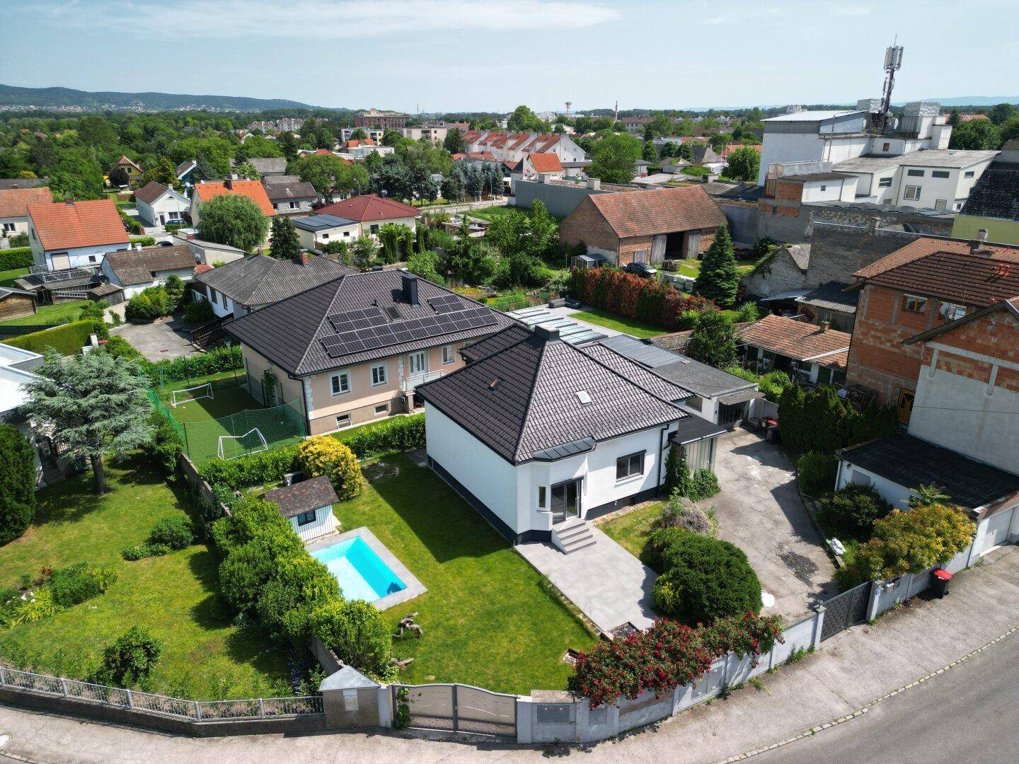Weitläufige Luftaufnahme des Anwesens mit Haus, Garten, Pool und umliegender Wohnbebauung.