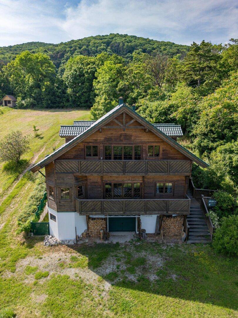 Frontansicht des Holzhauses mit mehreren Balkonen und traditioneller Holzfassade in grüner Umgebung.
