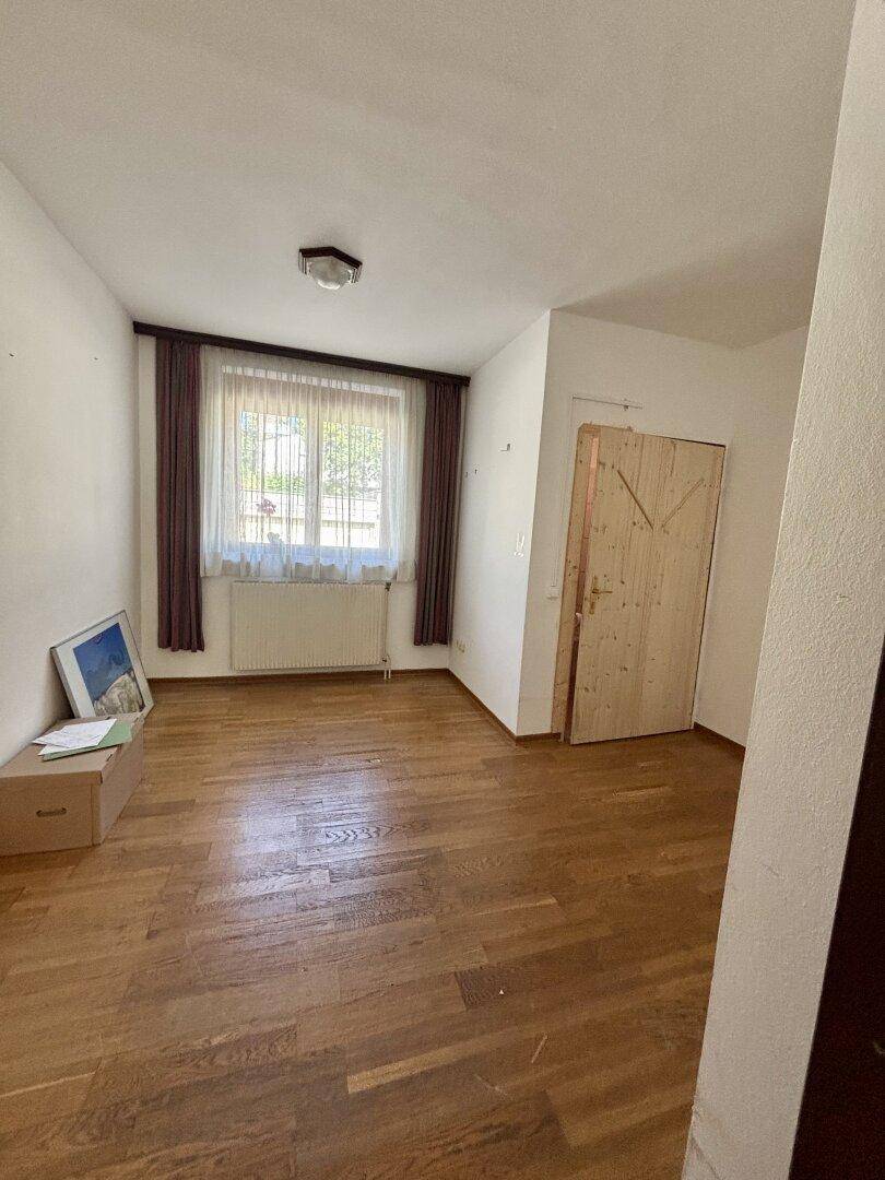 Schlafzimmer mit Parkettboden, Fenster und Heizkörper.