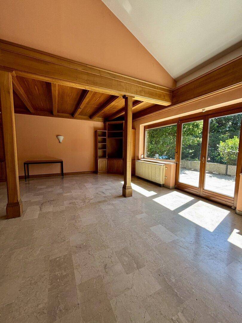 Heller Wohnraum mit großen Fenstern, Holzbalkendecke und direktem Zugang zur Terrasse.