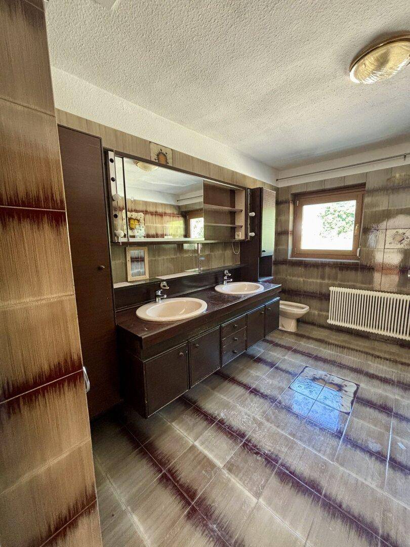 Badezimmer im 80er-Jahre-Stil mit Doppelwaschbecken, Bidet und gemusterten Fliesen.
