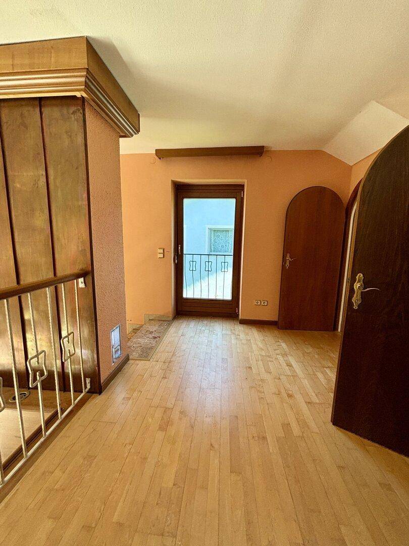 Oberer Flur mit Parkettboden und Tür zu einem französischen Balkon.