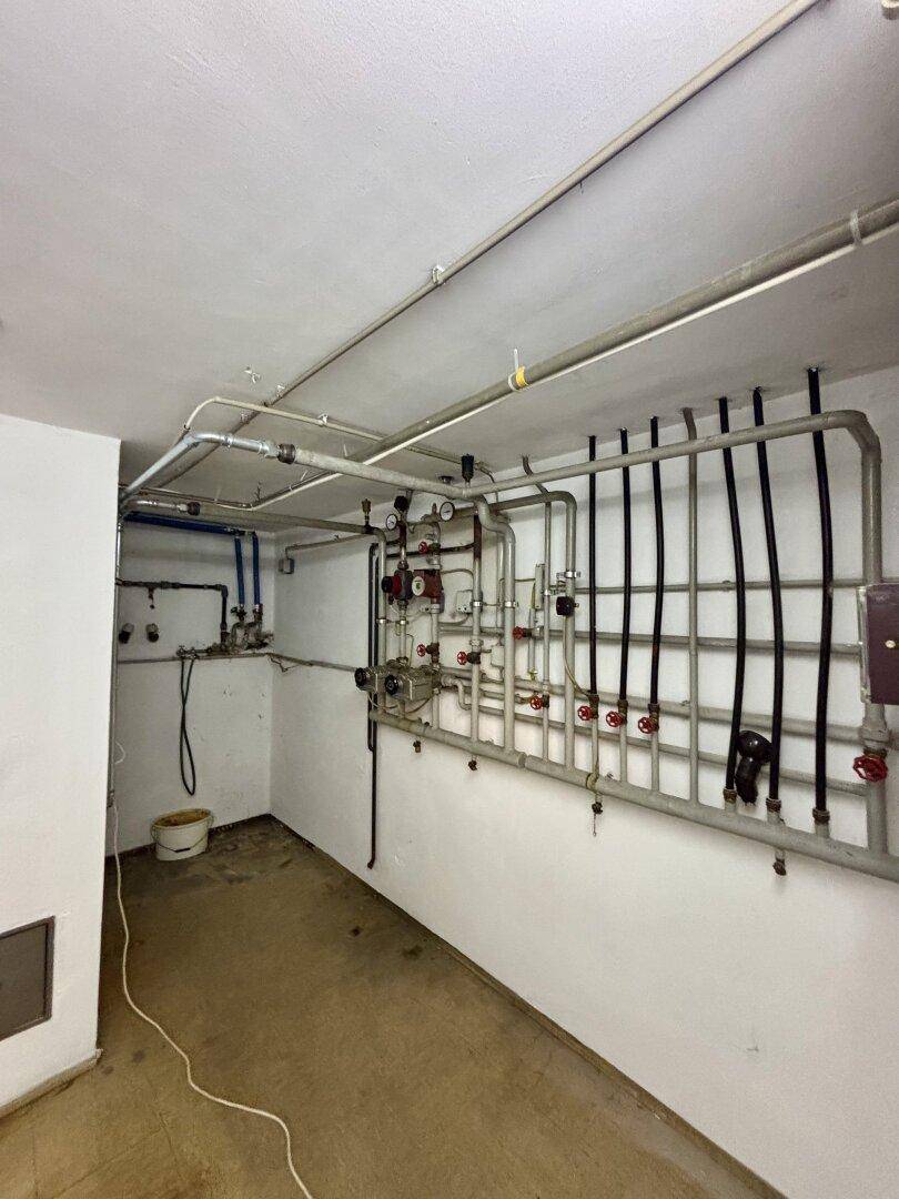 Technikraum mit umfangreicher Rohrinstallation und Heizungsanlage im Kellerbereich.