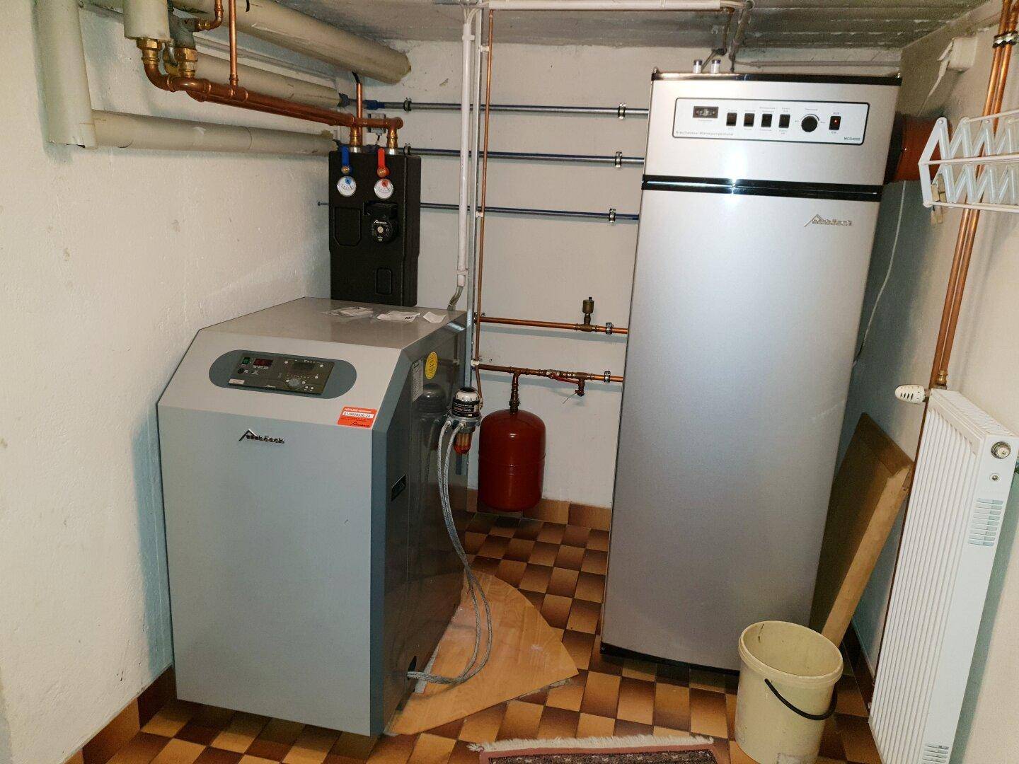 Heizungsraum mit zwei großen Heizkesseln und sichtbaren Rohrleitungen.