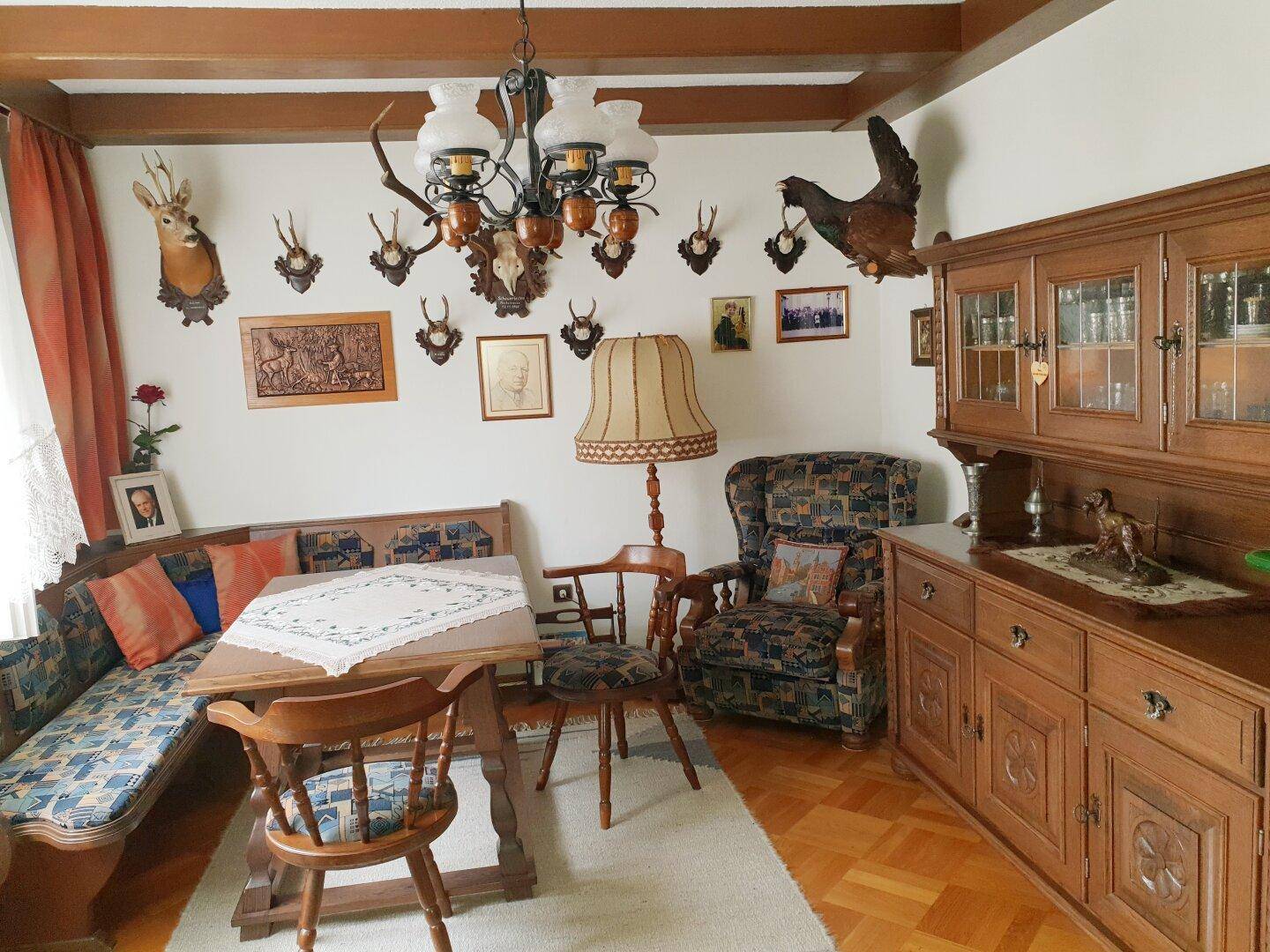 Rustikaler Essbereich mit Holztisch, Eckbank und traditioneller Jagdtrophäen-Dekoration.
