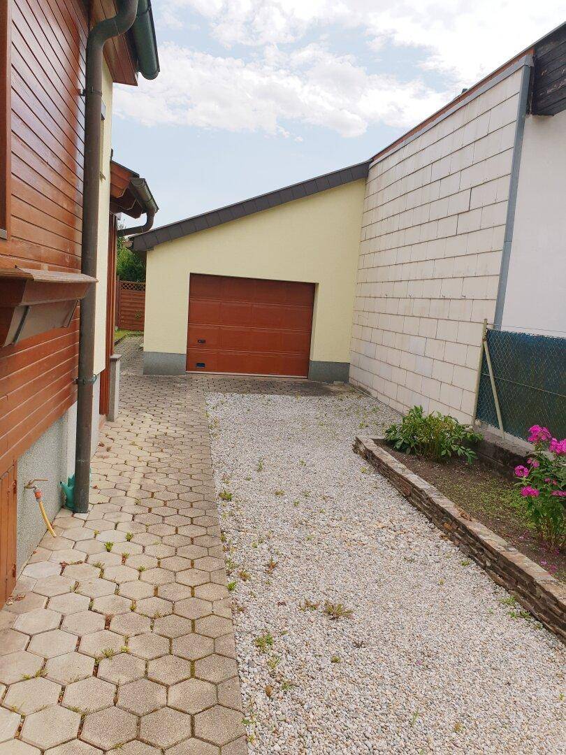 Zufahrt zum Haus mit Garage und gepflastertem Weg.