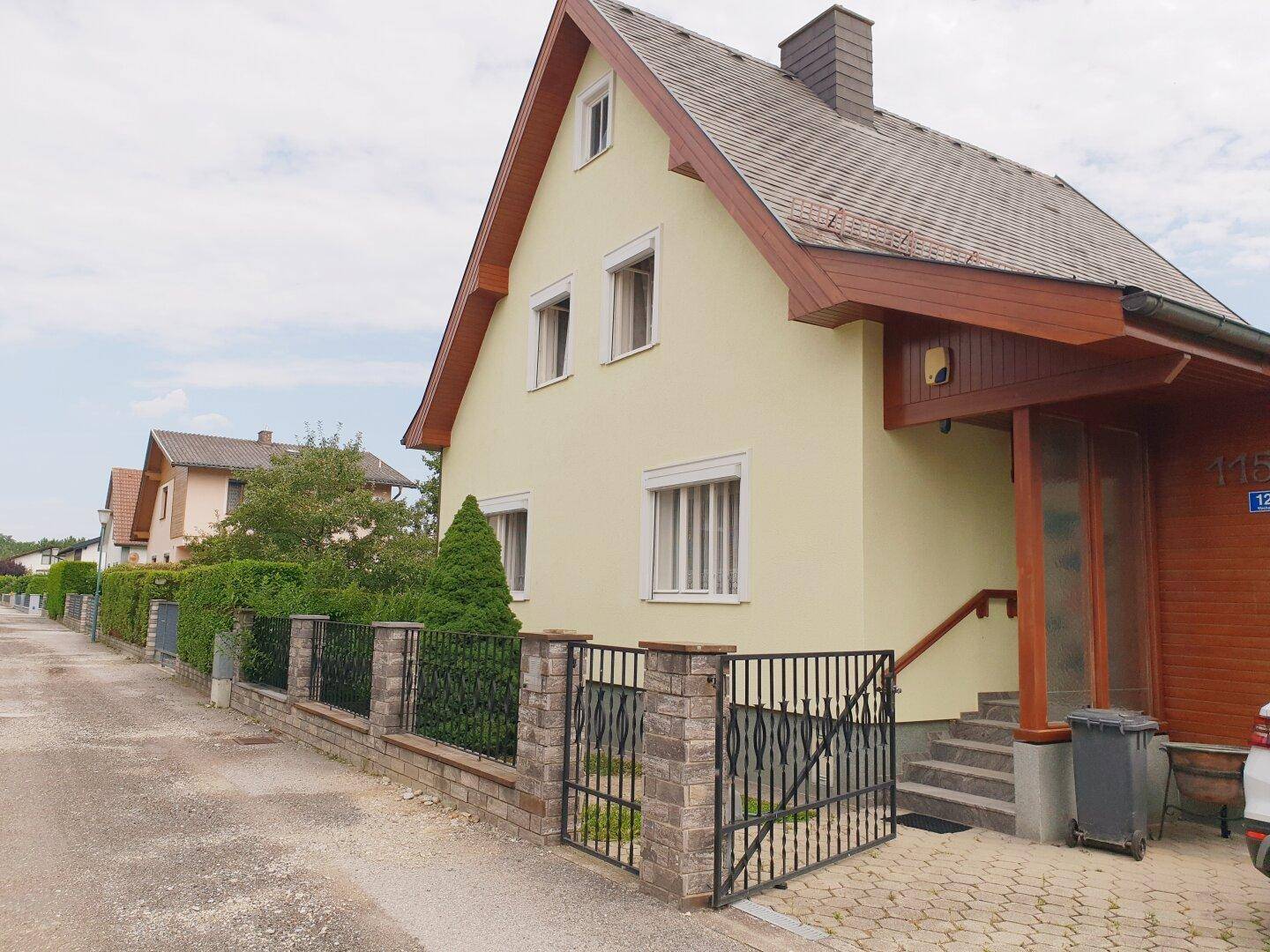Ansicht des Hauses von der Straße mit Zaun und gepflastertem Zugang.
