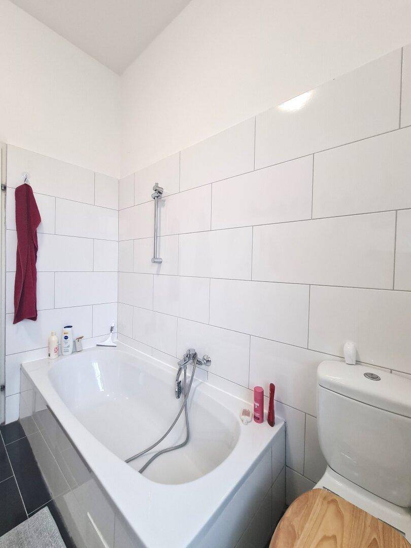 Badezimmer mit Badewanne, WC und weißen Wandfliesen, ideal für entspannende Momente.