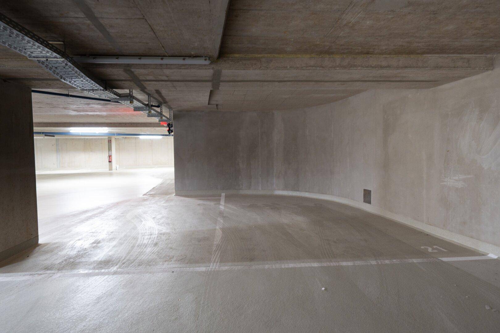 Tiefgarage mit Betonwänden und markierten Stellplätzen.
