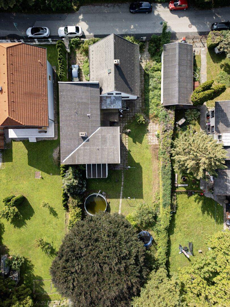 Draufsicht auf das Grundstück mit Haus, Garten, Pool und einem Trampolin im Grünen.