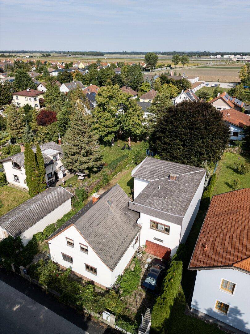 Überblick über ein Wohnviertel mit Einfamilienhäusern, umgeben von viel Grün und Feldern.