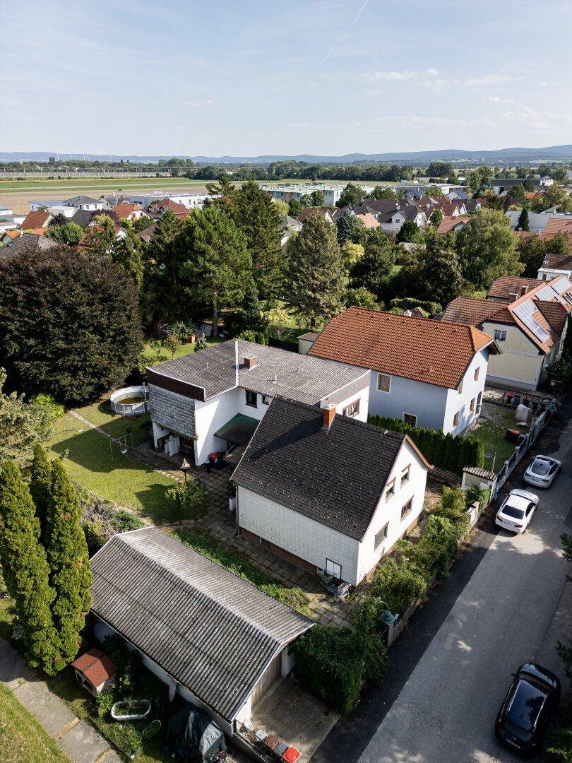Weitläufige Luftaufnahme eines Wohnviertels mit Häusern, Gärten und einer ruhigen Straße.