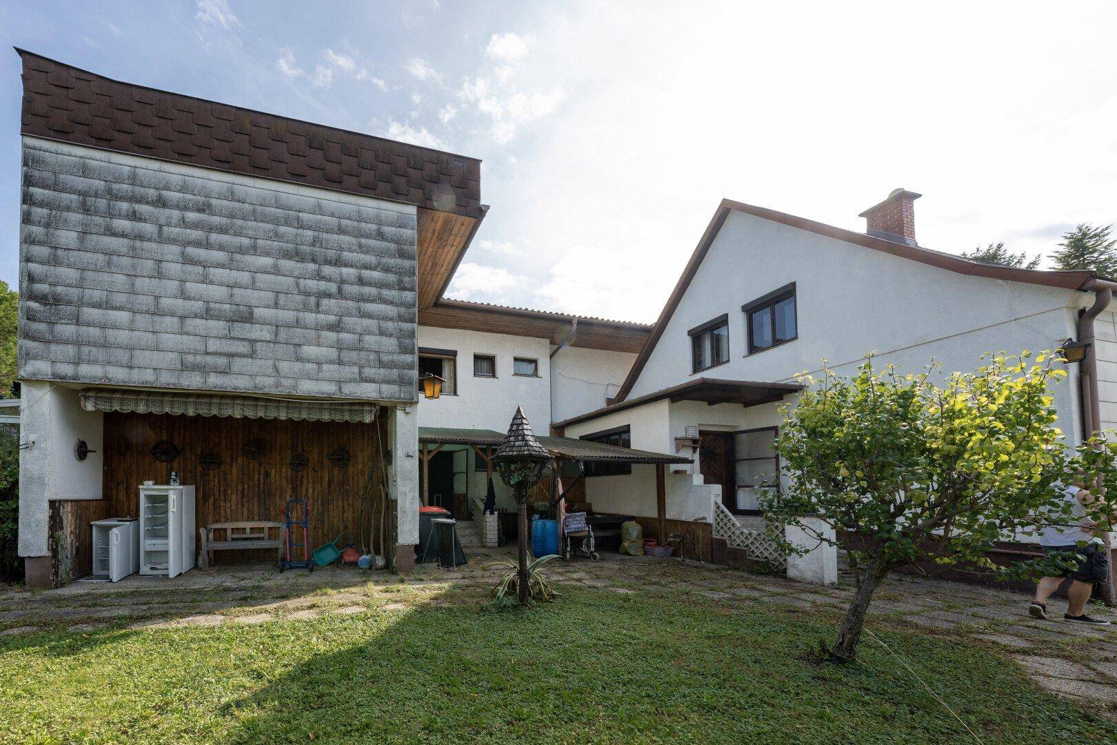Rückansicht des Hauses mit einer kleinen Terrasse und einem gepflegten Rasen im Garten.