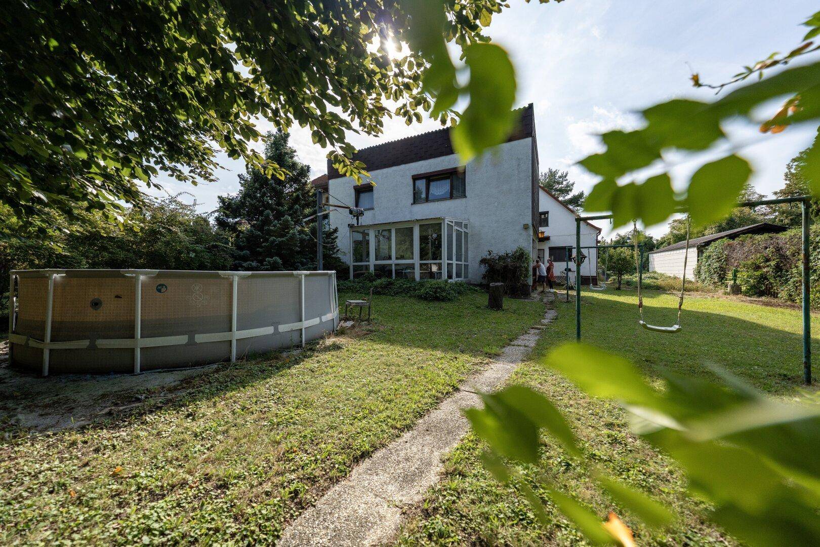 Hinterhof mit einem Aufstellpool, einer Schaukel und einem Wintergarten am Haus.