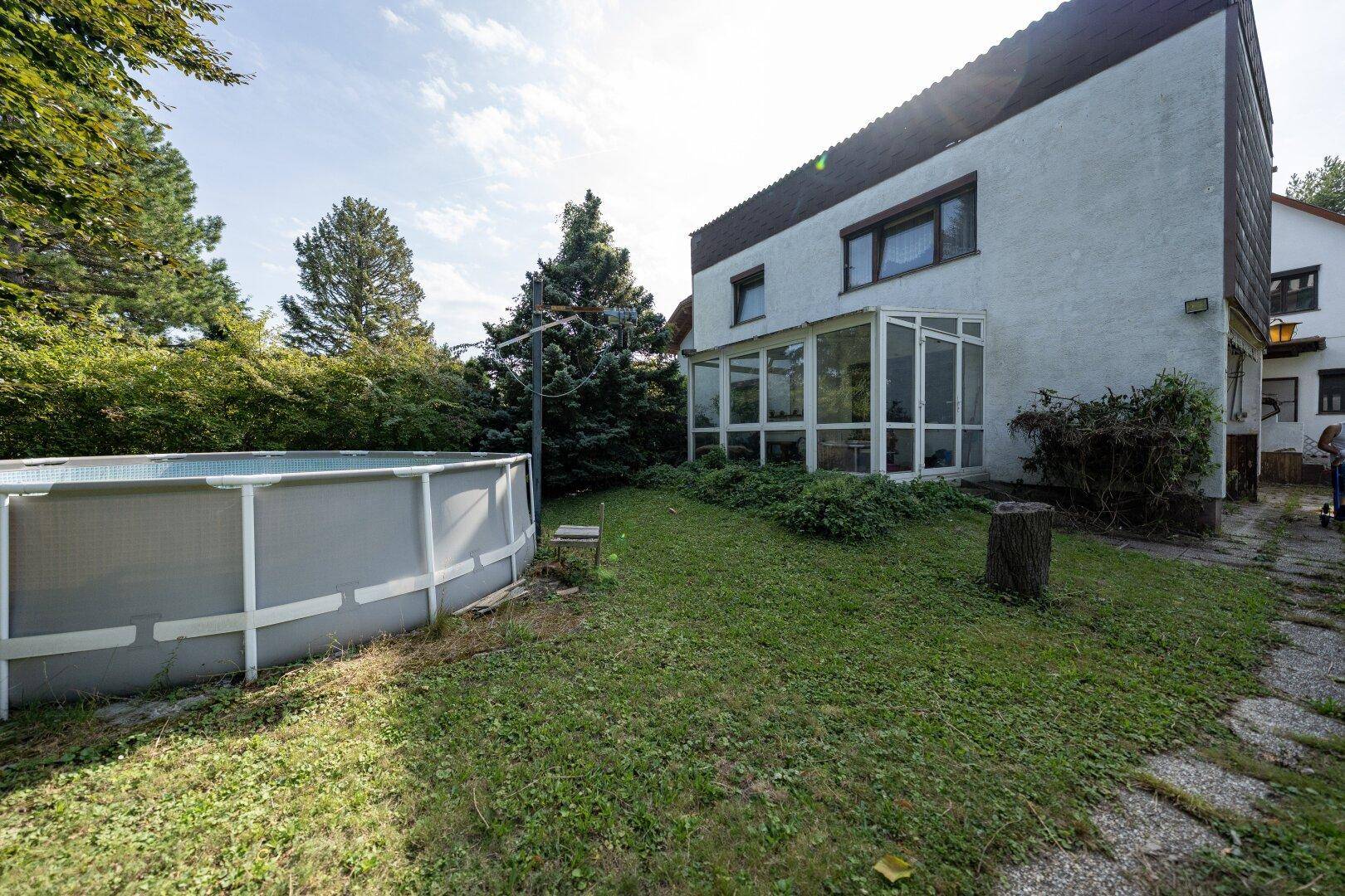 Gartenansicht mit Aufstellpool und dem angrenzenden Wintergarten des Hauses.