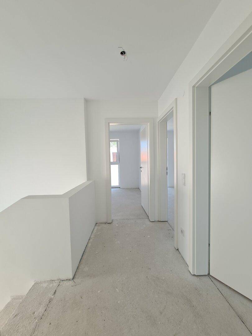 Heller Flur im Obergeschoss mit Zugang zu mehreren Zimmern und viel Tageslicht.