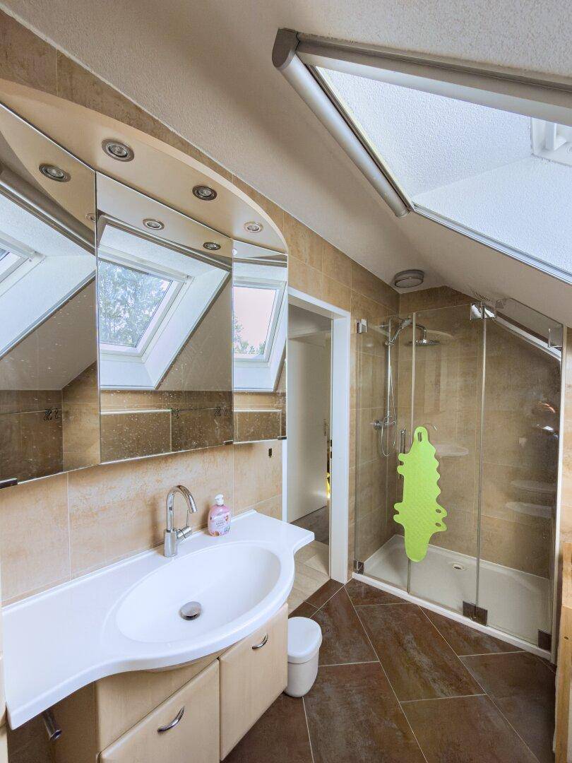 Modernes Badezimmer im Dachgeschoss mit begehbarer Dusche, Einzelwaschbecken und Dachfenster.