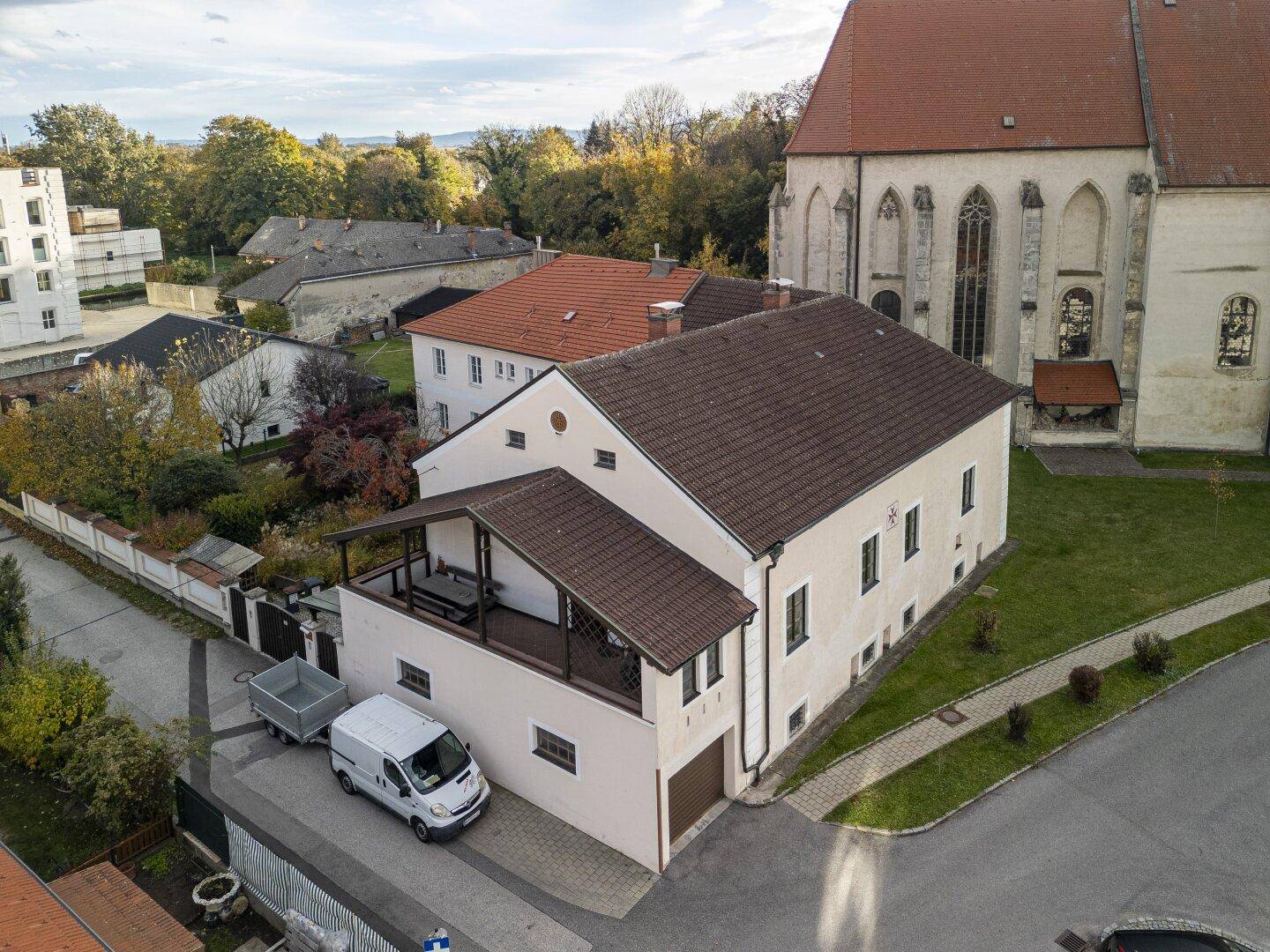 Seitenansicht des Gebäudes mit angrenzender Kirche und einem überdachten Außenbereich.