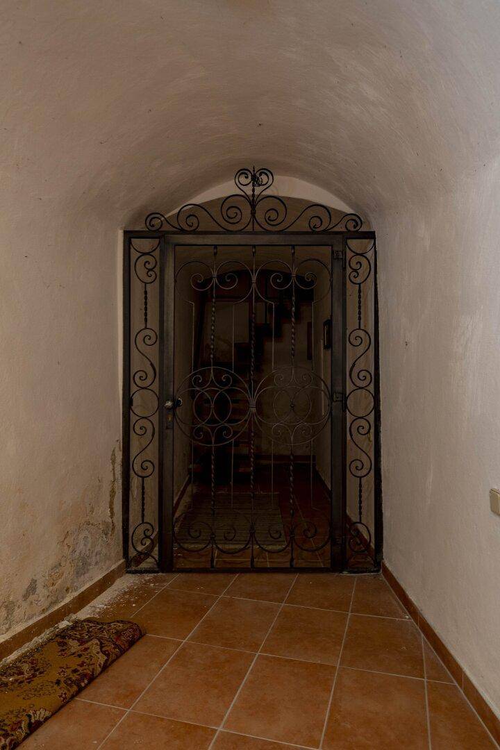 Historisches schmiedeeisernes Tor in einem Gewölbekeller, das einen weiteren Bereich abtrennt.