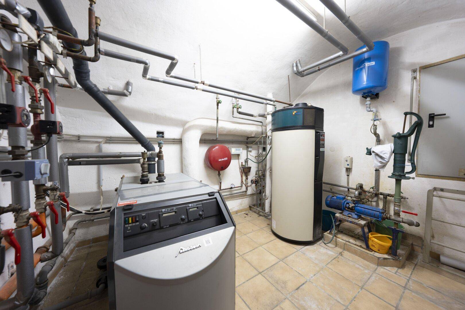 Heizungsraum mit komplexen Rohrleitungen, Heizkessel und Warmwasserspeicher.