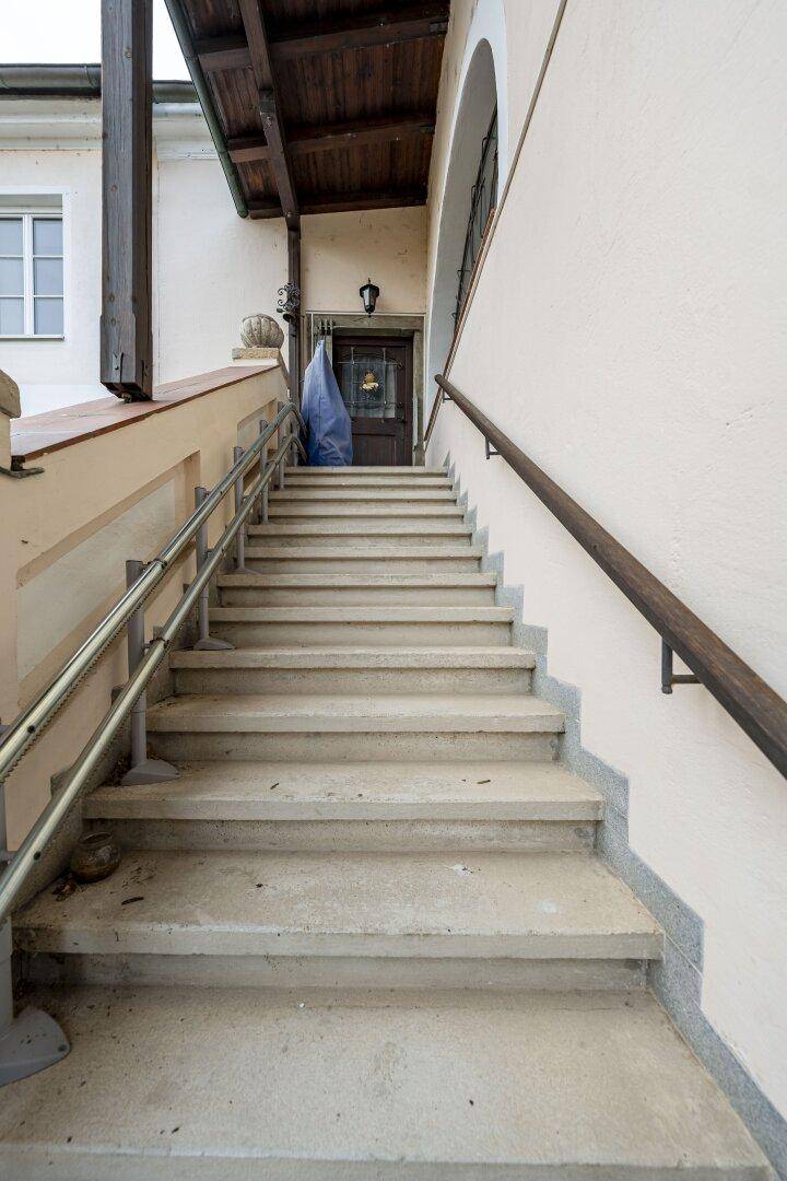 Außentreppe mit Handläufen, die zum Eingang des Gebäudes führt.