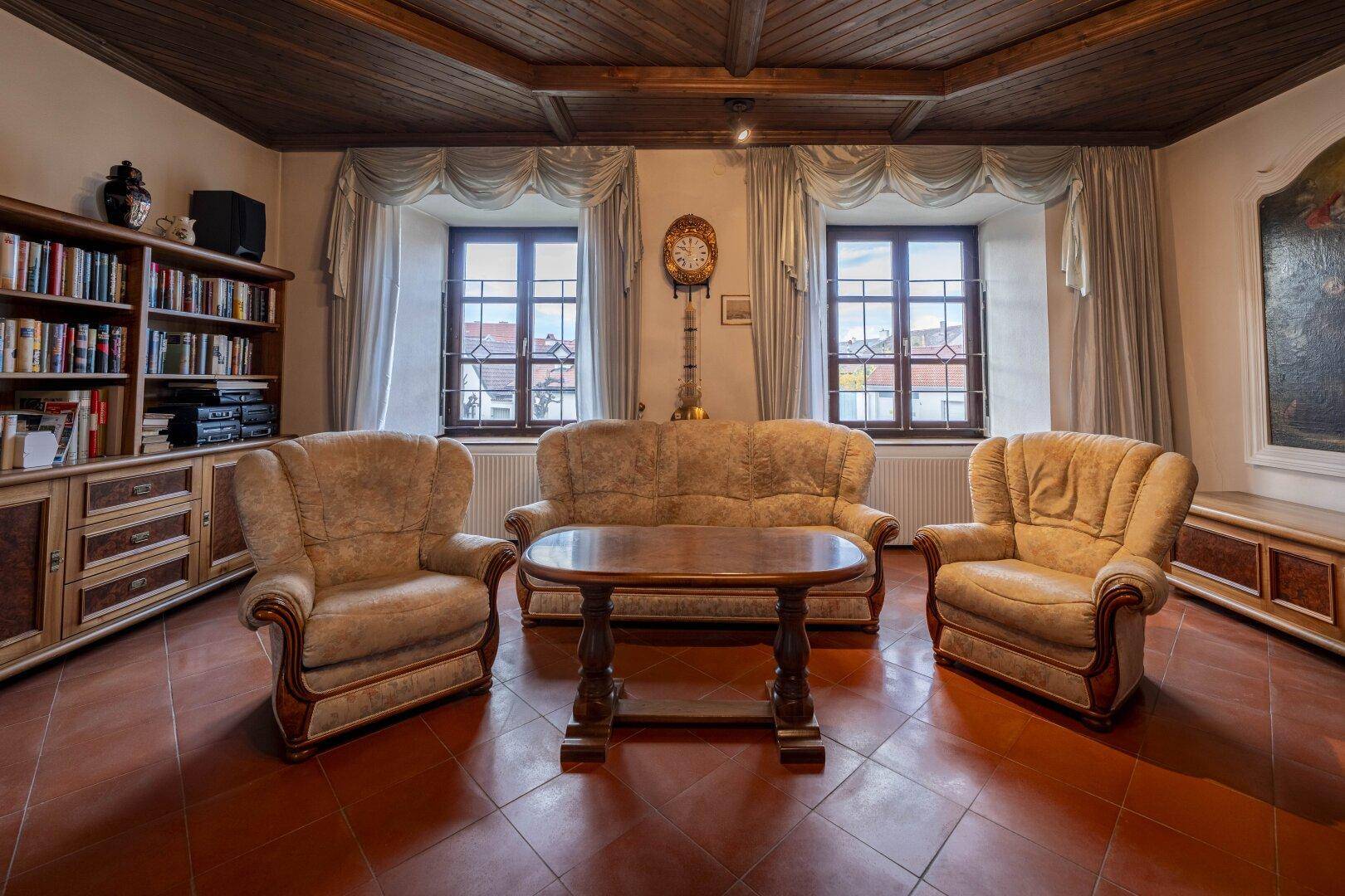 Gemütliches Wohnzimmer mit bequemen Sofas, Holztisch und Blick auf die Fenster.