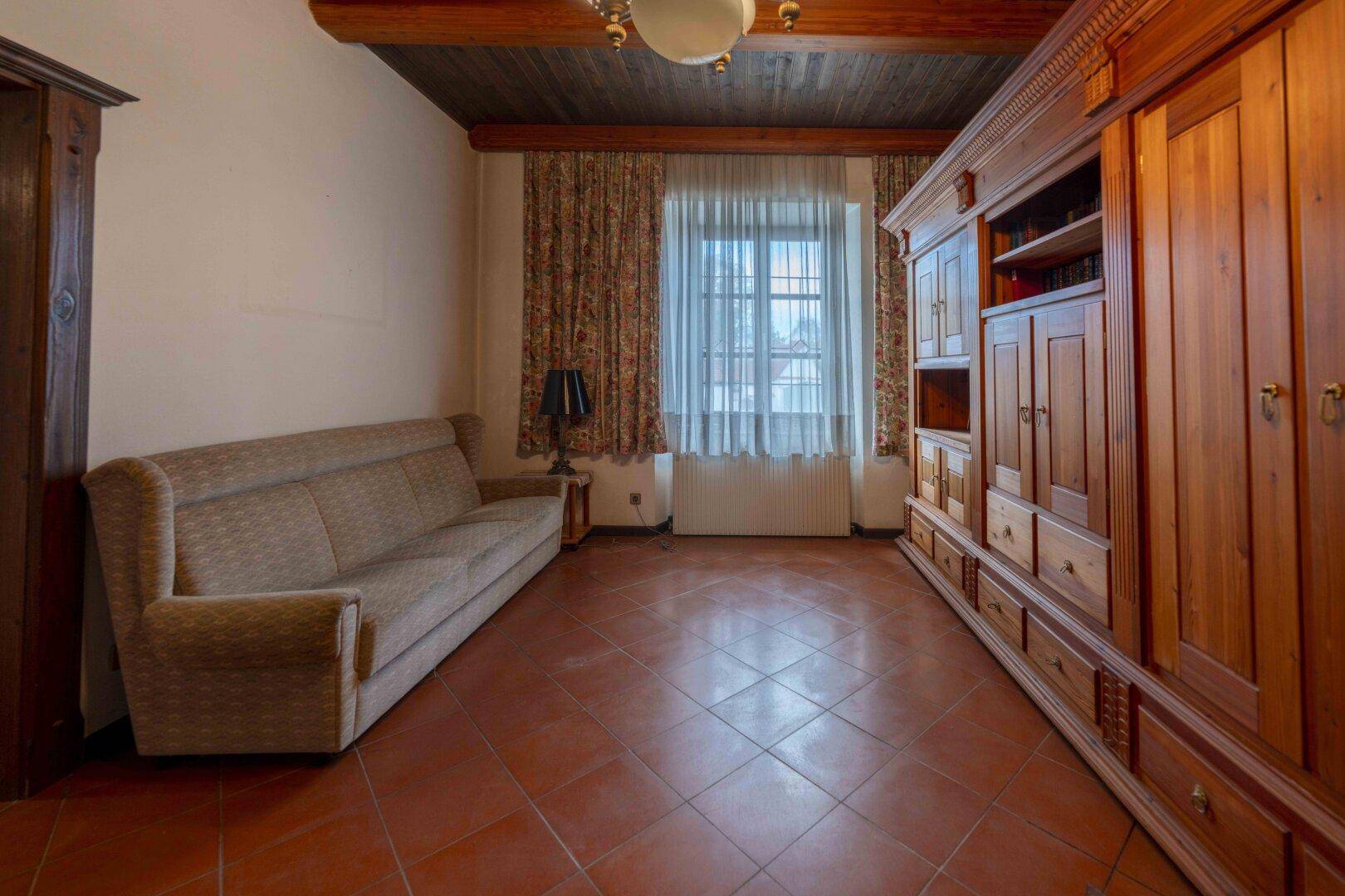 Schlafzimmer mit Terrakottafliesen, Holzbalkendecke und einem großen Einbauschrank.
