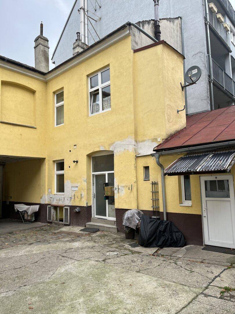 Detailansicht des Innenhofs mit einem Teil der gelben Gebäudefassade und einem kleinen Anbau.