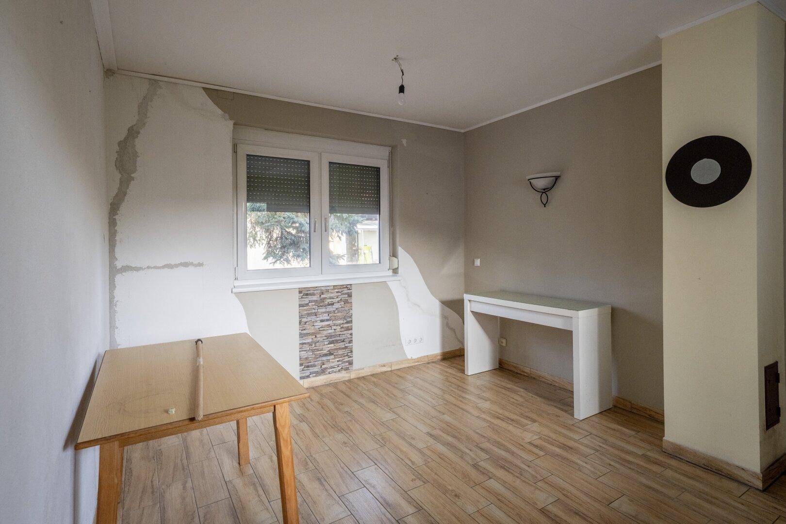 Raum mit Fliesenboden in Holzoptik und einem Fenster, bietet Potenzial für Esszimmer oder Büro.