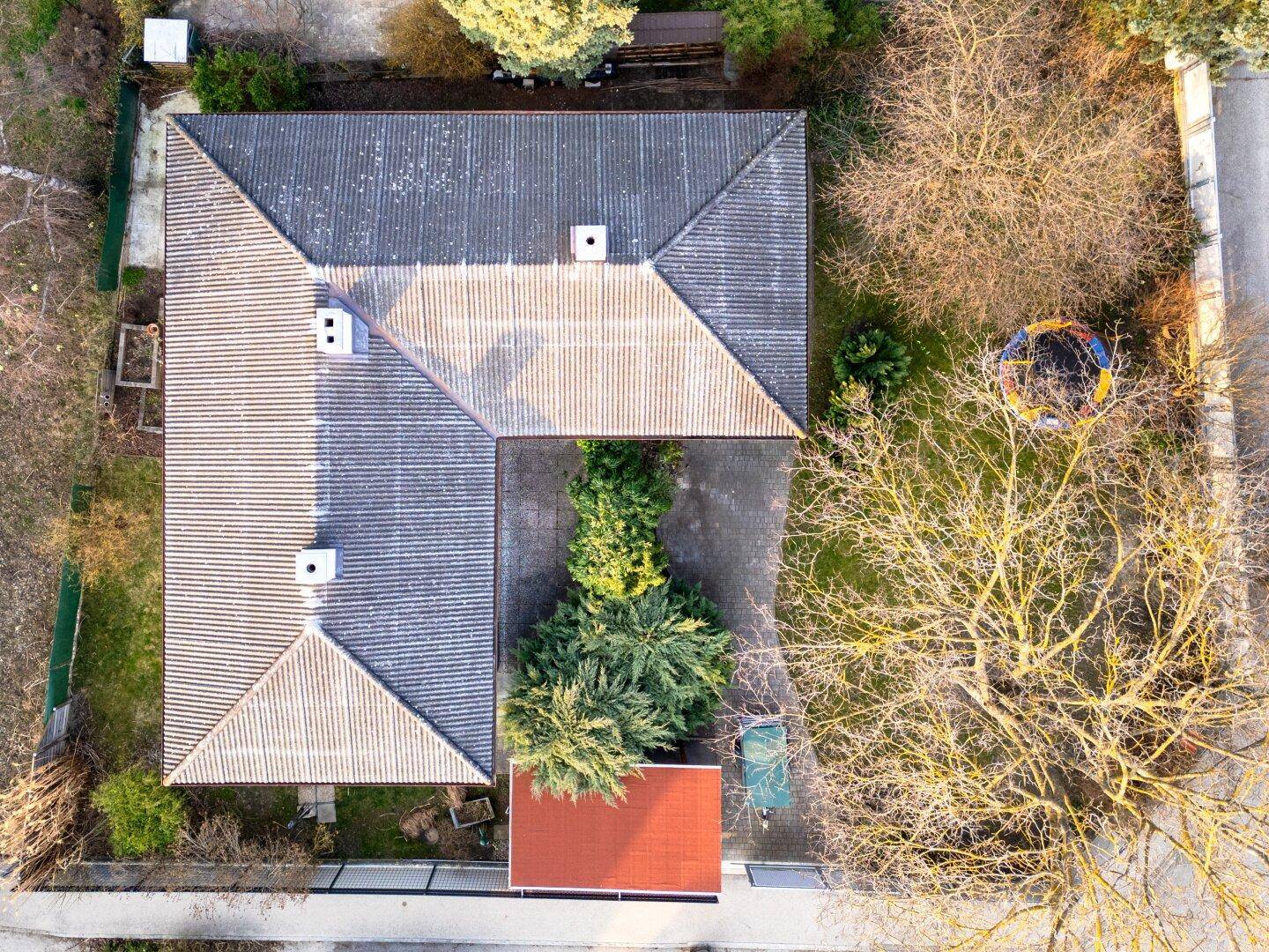 Draufsicht auf das Haus mit Satteldach, Garten und einem Trampolin im hinteren Bereich.