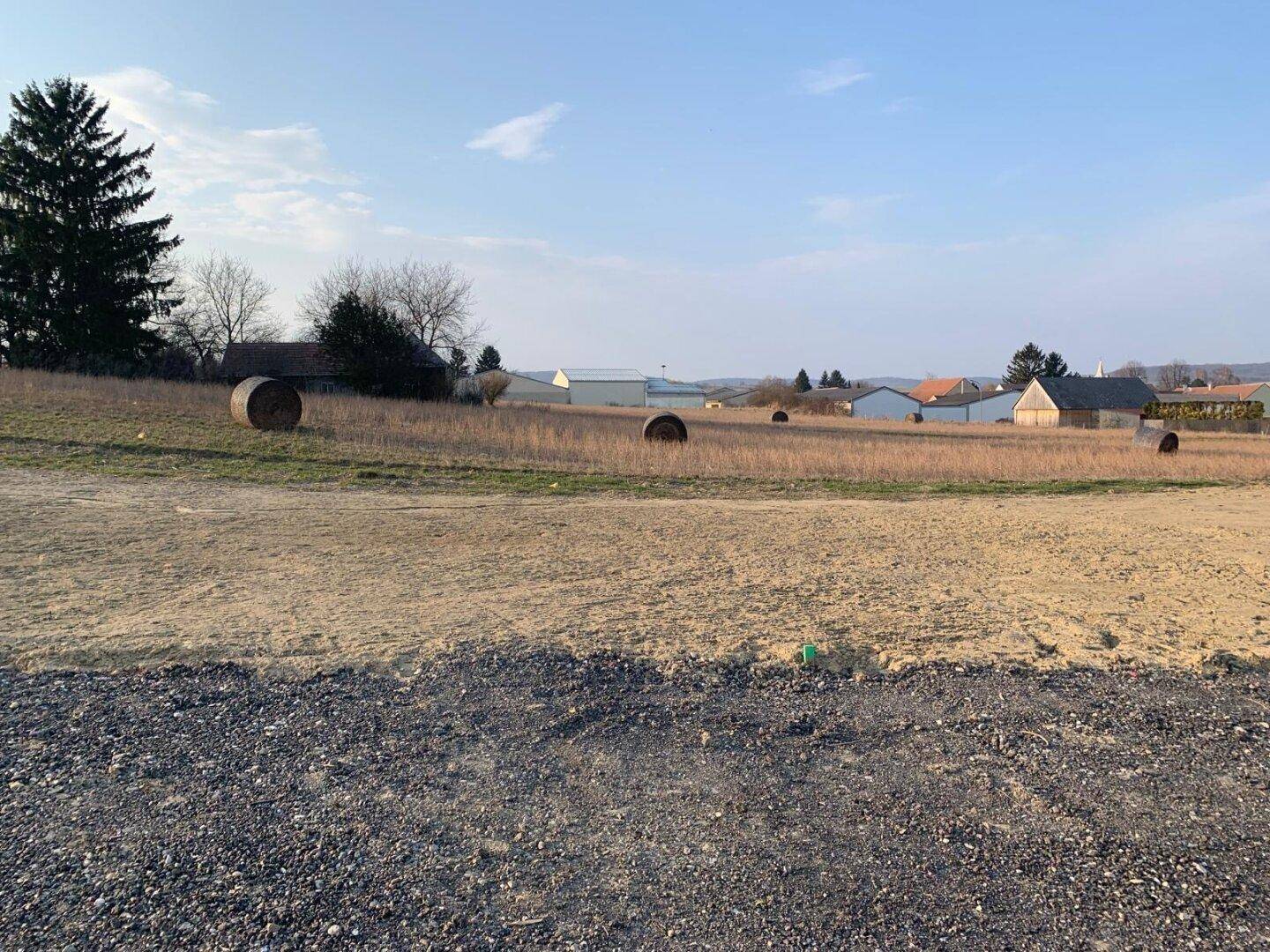 Offenes Baugrundstück mit Heuballen und weitem Blick über die Landschaft.