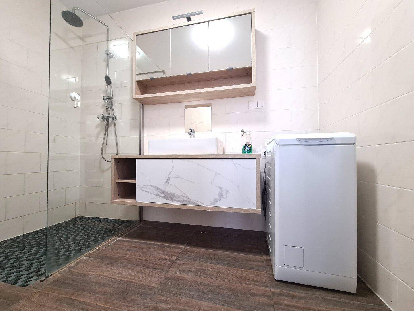 Modernes Badezimmer mit ebenerdiger Dusche, Waschbecken und Waschmaschine.