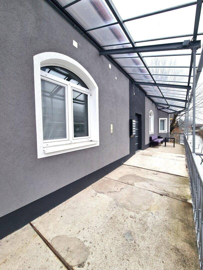 Überdachte Terrasse mit Sitzgelegenheiten und Blick auf die Umgebung.