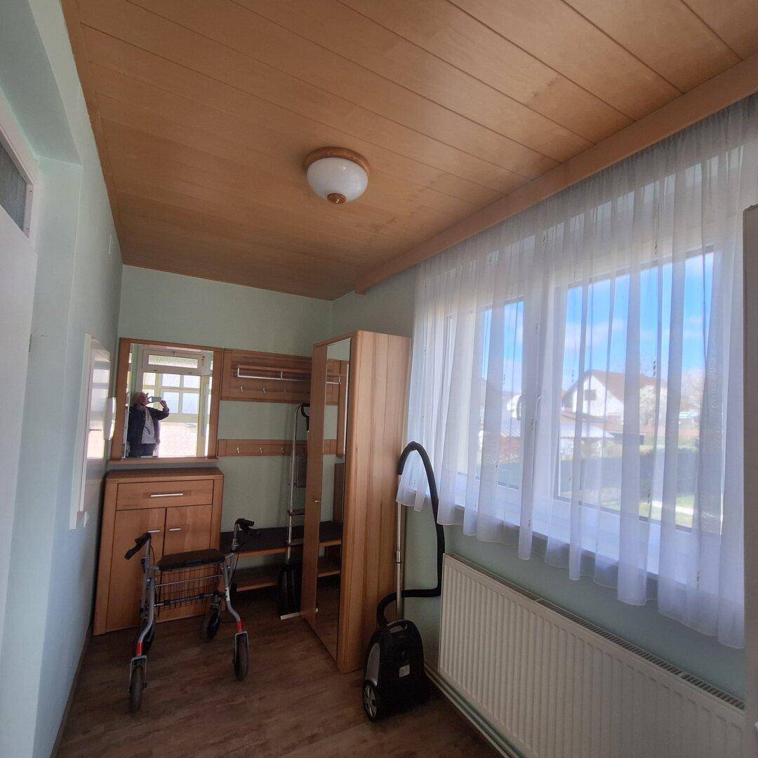 Freundlicher Flur mit Holzdecke, großem Fenster und Garderobenmöbeln.