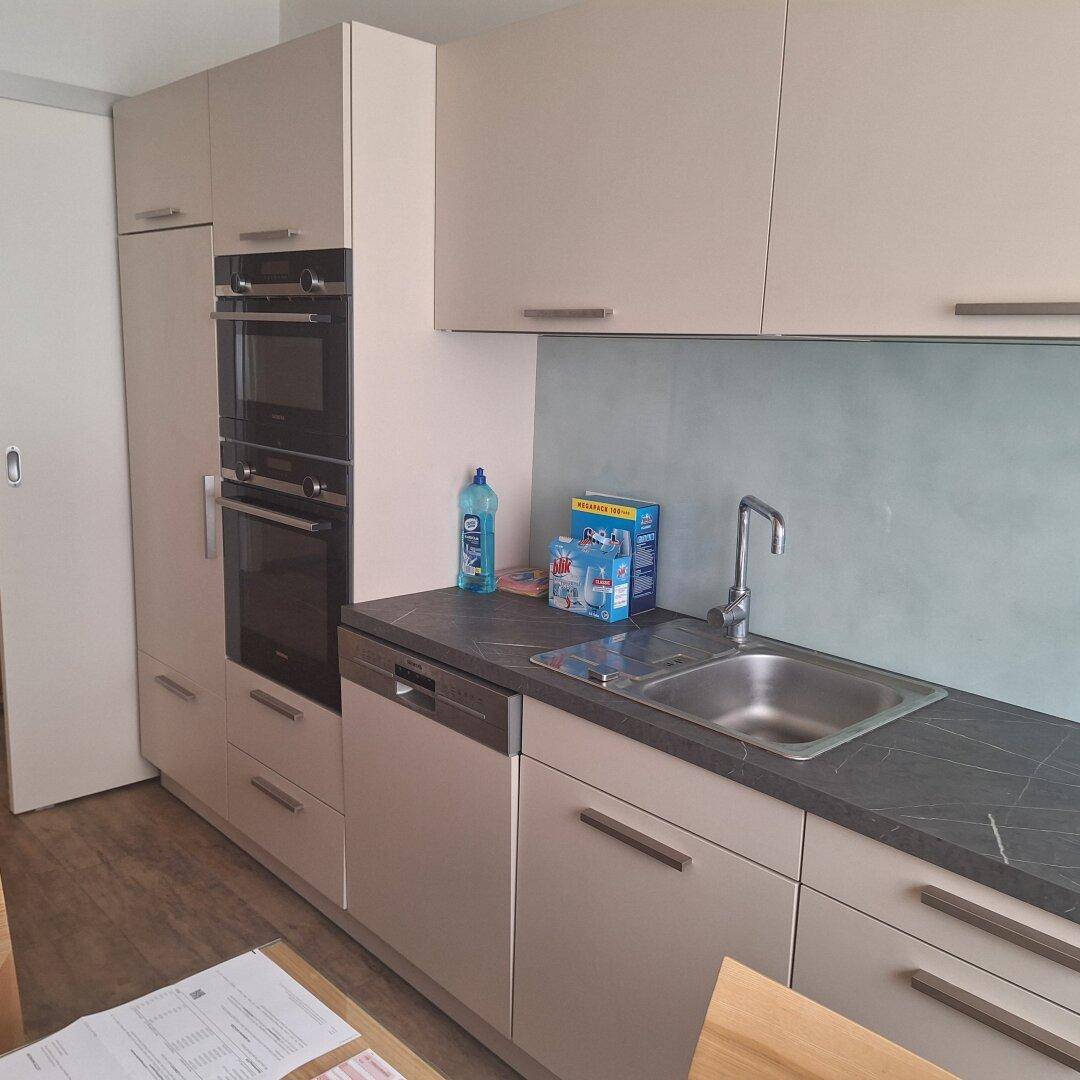 Moderne Einbauküche mit integriertem Backofen, Mikrowelle und Geschirrspüler.