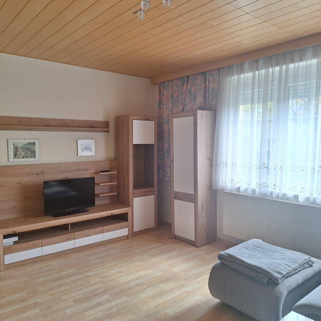 Helles Wohnzimmer mit Holzdecke, TV-Möbeln und großem Fenster.