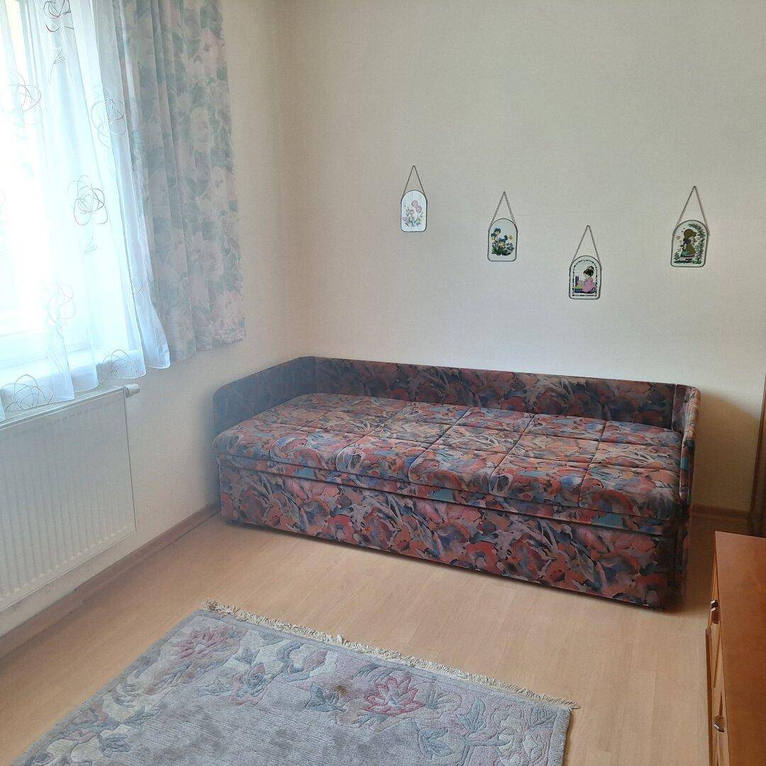 Schlafzimmer mit Schlafsofa, Fenster und hellem Laminatboden.