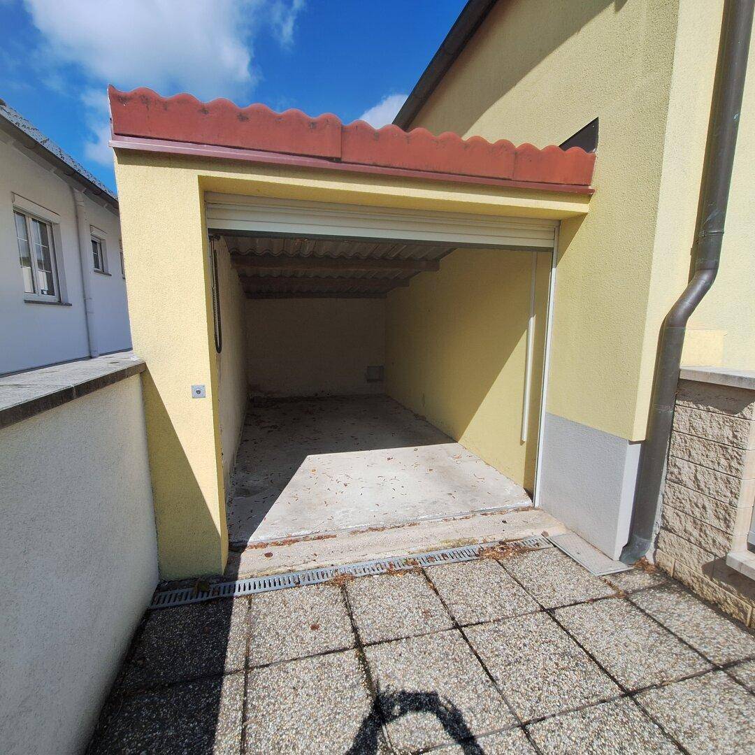 Leere Garage mit Betonboden und offenem Rolltor.