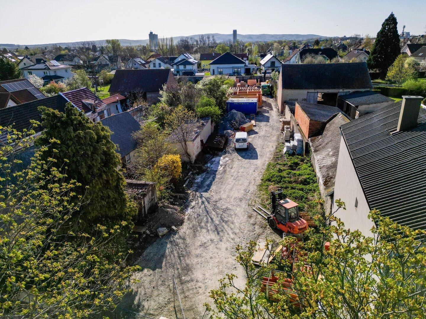 Luftaufnahme einer Wohnstraße in ländlicher Umgebung mit Häusern und Baustellen.