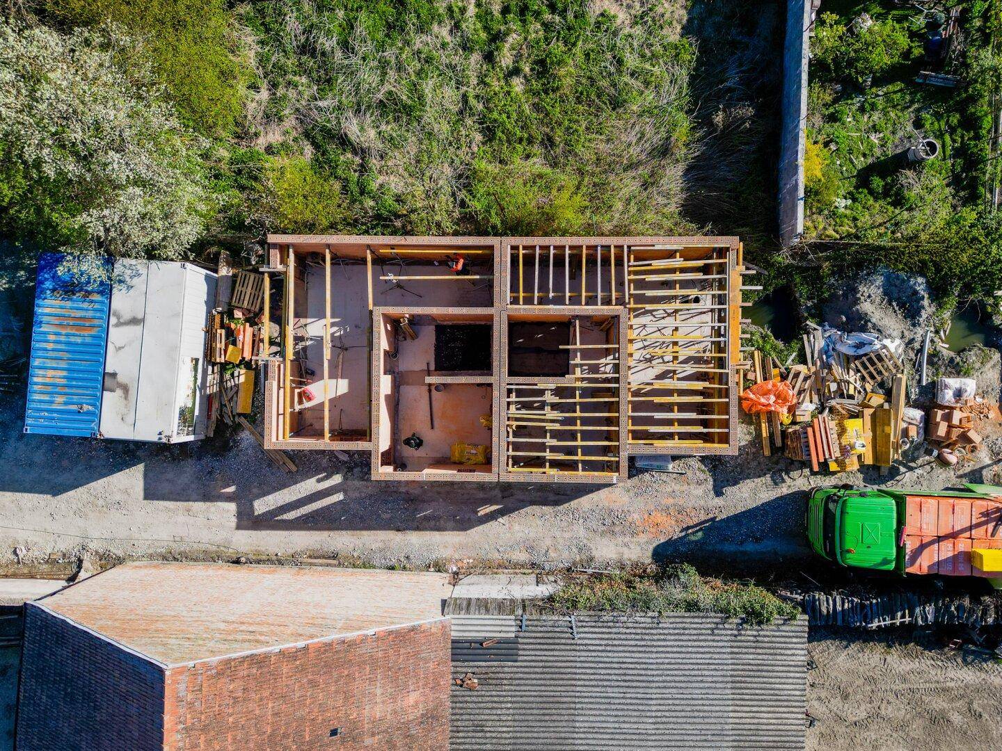 Luftaufnahme einer Baustelle, die den Holzrahmenbau eines im Bau befindlichen Hauses zeigt.