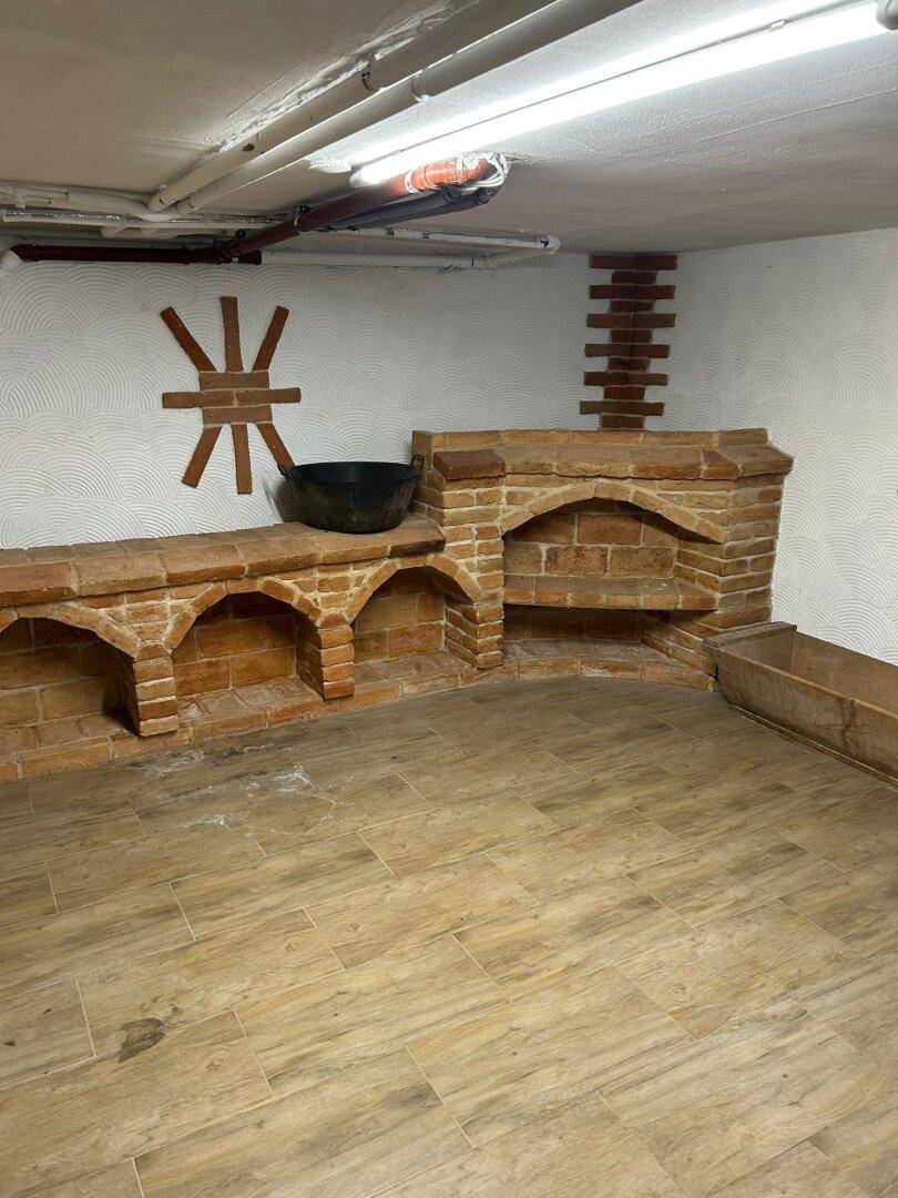 Kellerraum mit dekorativen Ziegelsteinbögen und Holzoptik-Fliesenboden.