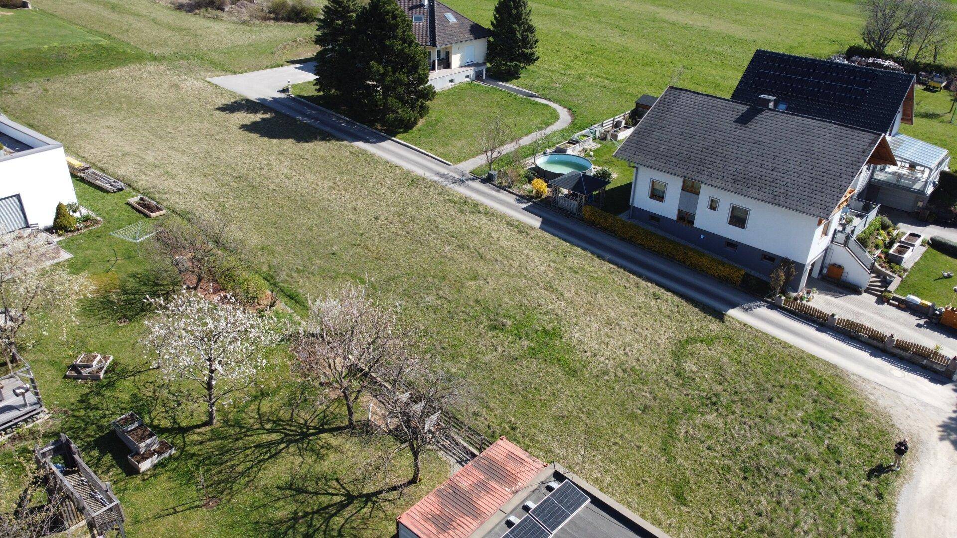Übersicht aus der Vogelperspektive auf das unbebaute Grundstück und die angrenzenden Häuser mit Gärten.