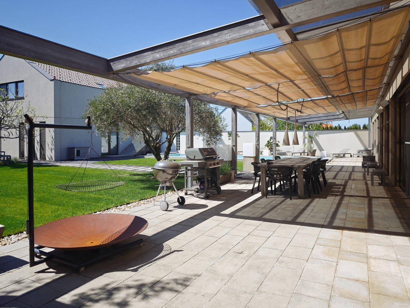 Geräumige Terrasse mit Essbereich, Grill und Feuerstelle, ideal für Outdoor-Unterhaltung.