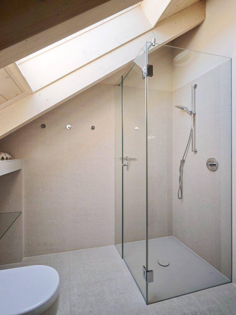 Geräumige begehbare Dusche im Dachgeschoss-Badezimmer mit Glaswänden und Dachfenster.