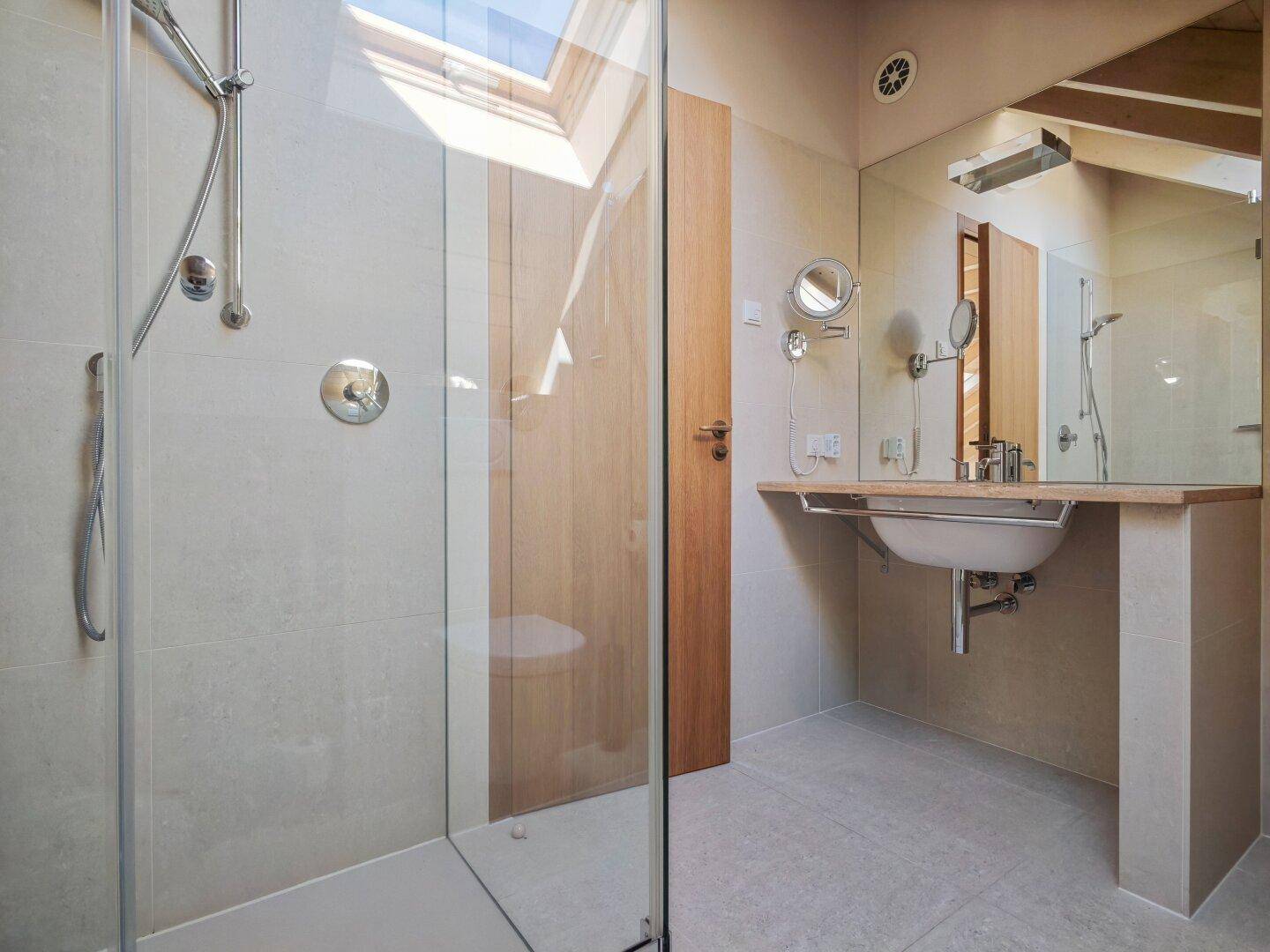 Modernes Badezimmer im Dachgeschoss mit begehbarer Dusche, Waschbecken und Dachfenster.
